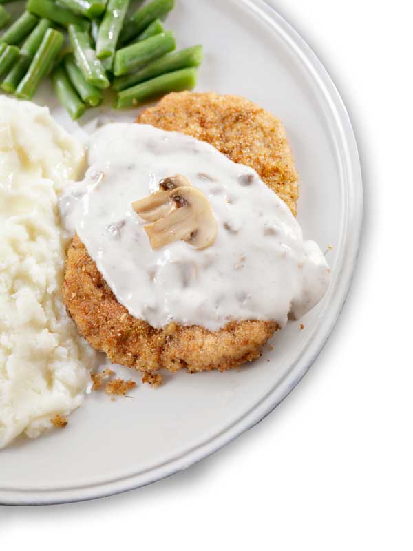 Denny's country fried steak on a plate with mashed potatoes and green beans