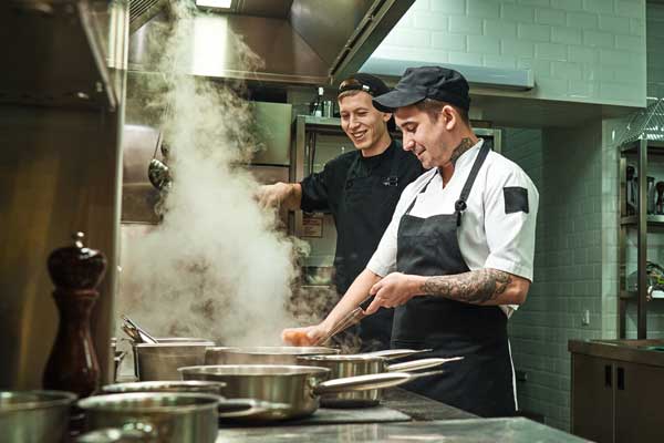 Two smiling chefs cooking in a commercial kitchen