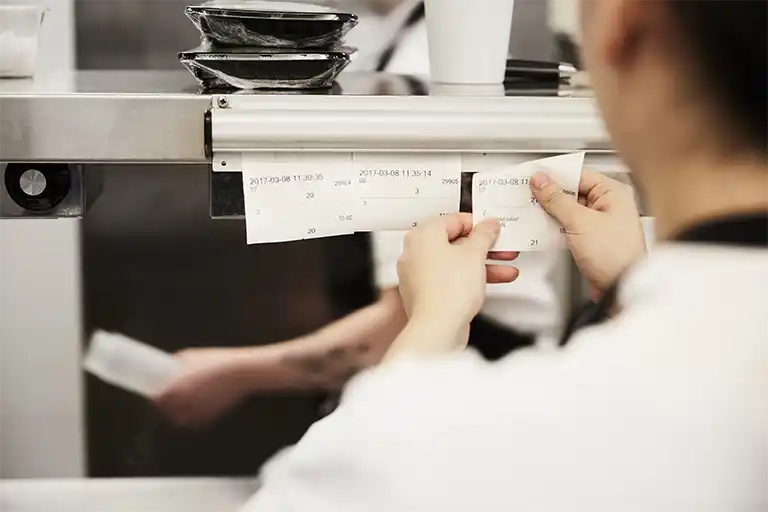 Chef reading order paper in a busy restaurant